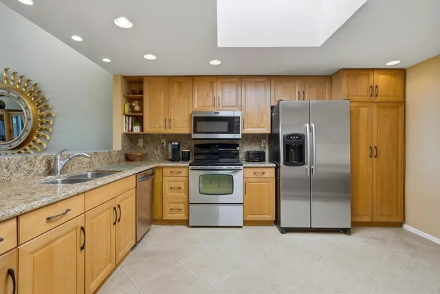 a kitchen with stainless steel appliances granite countertop a refrigerator a stove and a sink with wooden floor