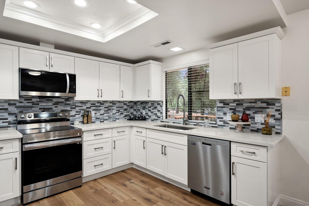 6561 Trinity Way Placerville, CA 95667 - Photo 2 of 58 a kitchen with stainless steel appliances granite countertop a stove top oven a sink dishwasher and white cabinets with wooden floor