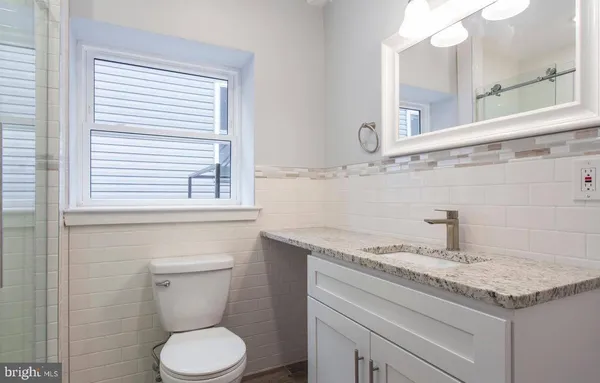 a bathroom with a granite countertop sink toilet and mirror