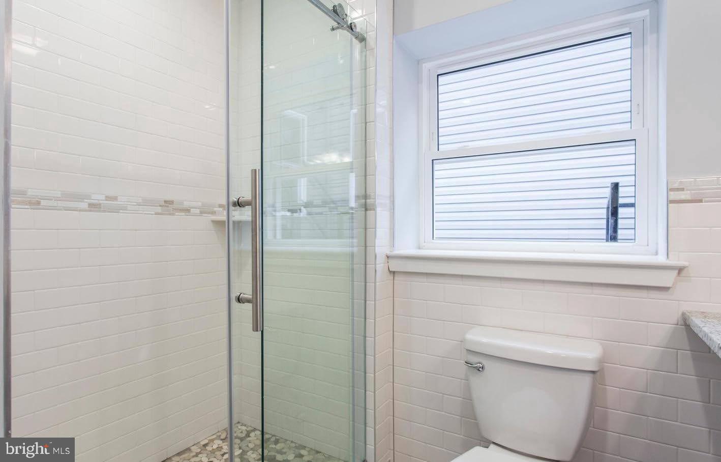 1318 South Broad Street, Unit 2R Philadelphia, PA 19146 - Photo 8 of 11 a bathroom with a toilet a sink and a window