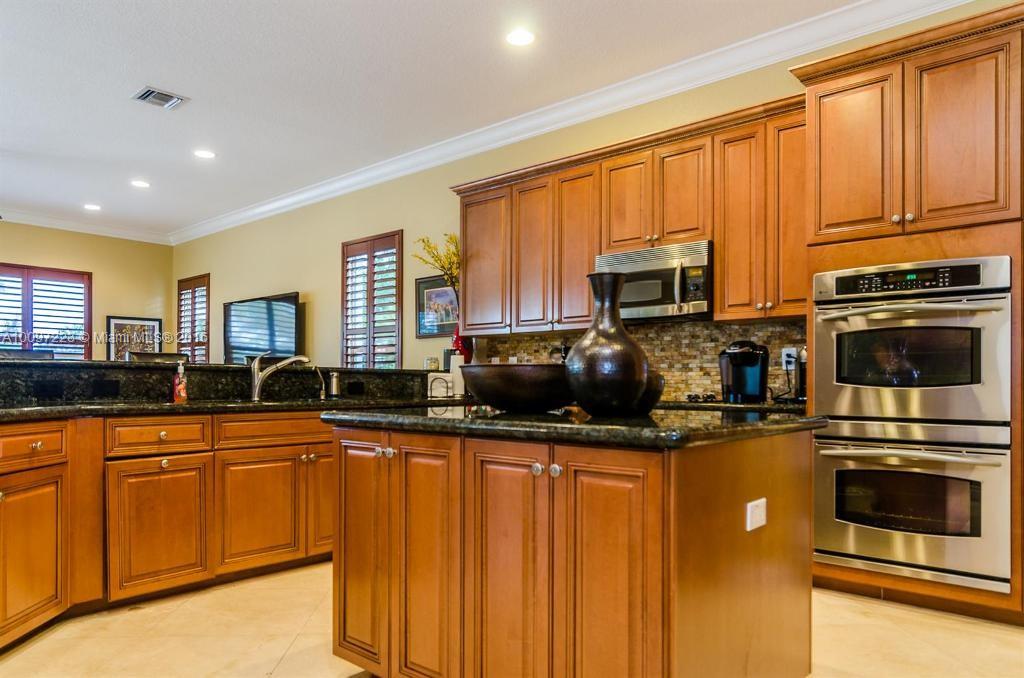 2633 Birch Terrace Davie, FL 33330 - Photo 9 of 35 a kitchen with granite countertop stainless steel appliances a stove sink microwave and cabinets
