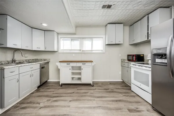 a kitchen with granite countertop a stove a sink and white cabinets