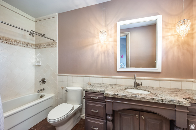 694 West Cephus Road Draper, UT 84020 - Photo 64 of 148 Bathroom featuring a built-in tub with tile surround, a low-profile toilet, a vanity with a light-toned countertop, an undermount sink, and two decorative pendant lights