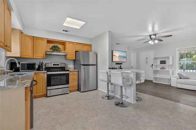 a kitchen with stainless steel appliances kitchen island granite countertop a refrigerator a stove a sink dishwasher with a dining table and chairs with wooden floor