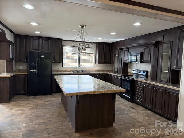 a kitchen with stainless steel appliances granite countertop a refrigerator a sink a stove a microwave and wooden cabinets