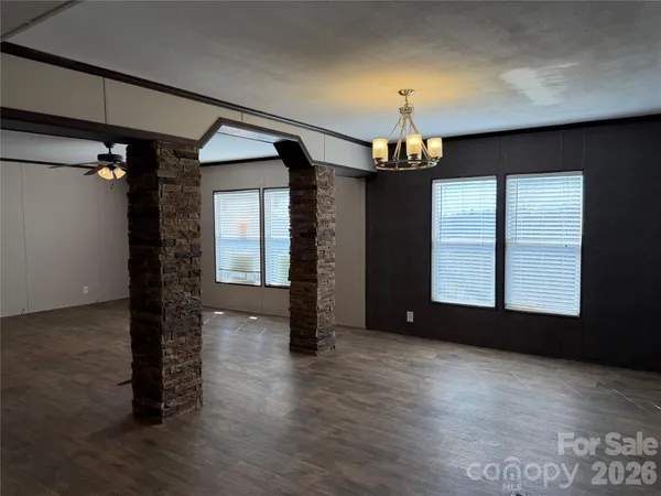 a view of a room with wooden floor chandelier and windows
