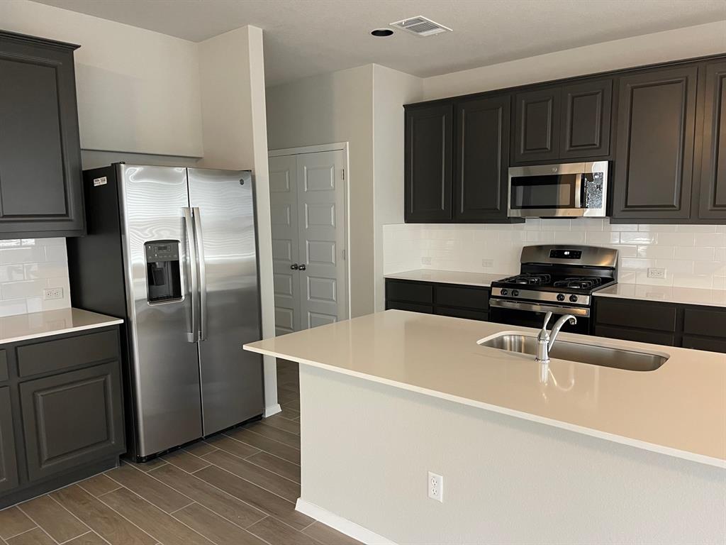 100 Crescent Street Georgetown, TX 78626 - Photo 3 of 17 a kitchen with wooden cabinets a sink and stainless steel appliances