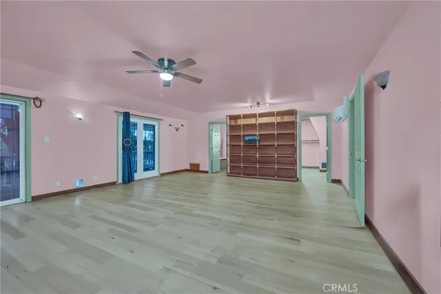 a view of an empty room with window and wooden floor