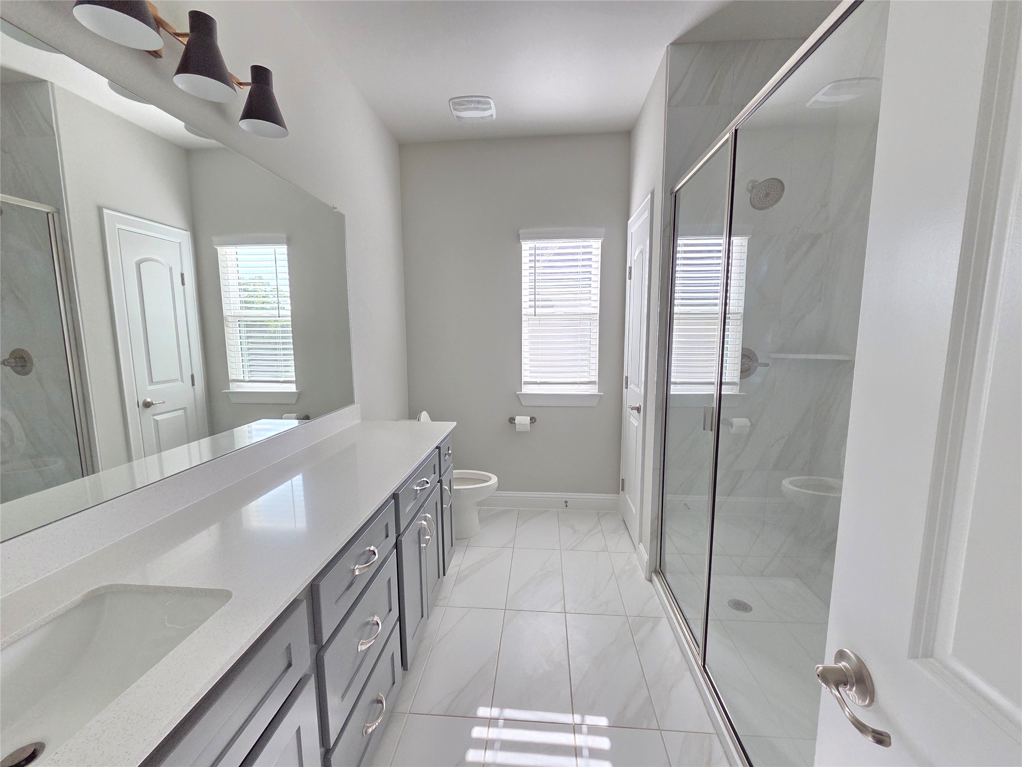 600 C-Bar Ranch Trail, Unit 121 Cedar Park, TX 78613 - Photo 26 of 32 A well-lit primary bathroom featuring a spacious vanity with dual sinks, a large mirror, and a glass-enclosed shower.