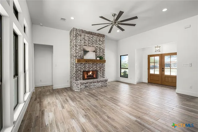 a kitchen with stainless steel appliances a stove top oven a sink dishwasher a refrigerator and a dining table with wooden floor