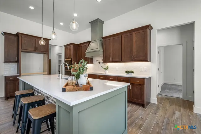a kitchen with stainless steel appliances granite countertop a kitchen island hardwood floor sink stove and refrigerator