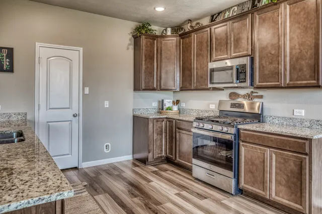 a kitchen with stainless steel appliances granite countertop a stove a sink and a refrigerator with wooden cabinets