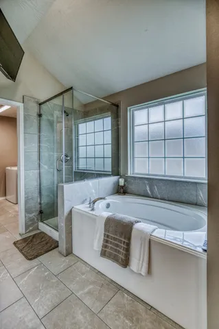 a spacious bathroom with a tub a mirror and a shower