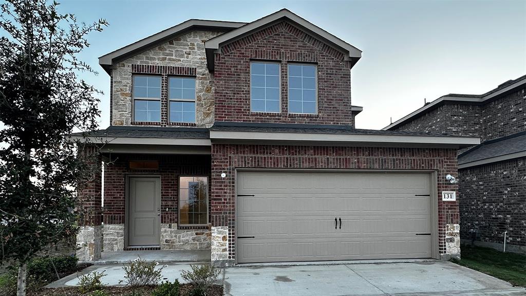 Two-story residence featuring a brick and stone facade, covered front porch, an attached garage, and multiple windows