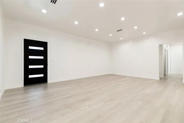 a view of an empty room with wooden floor and closet