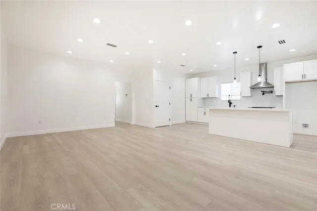 a large white kitchen with kitchen island a sink a stove and a refrigerator
