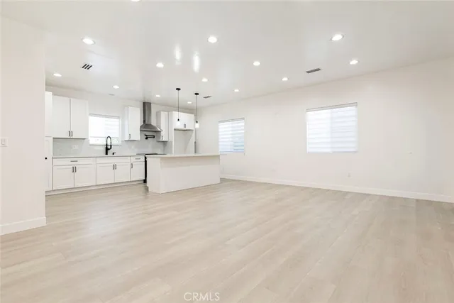 a large white kitchen with kitchen island a sink wooden floor and white cabinets