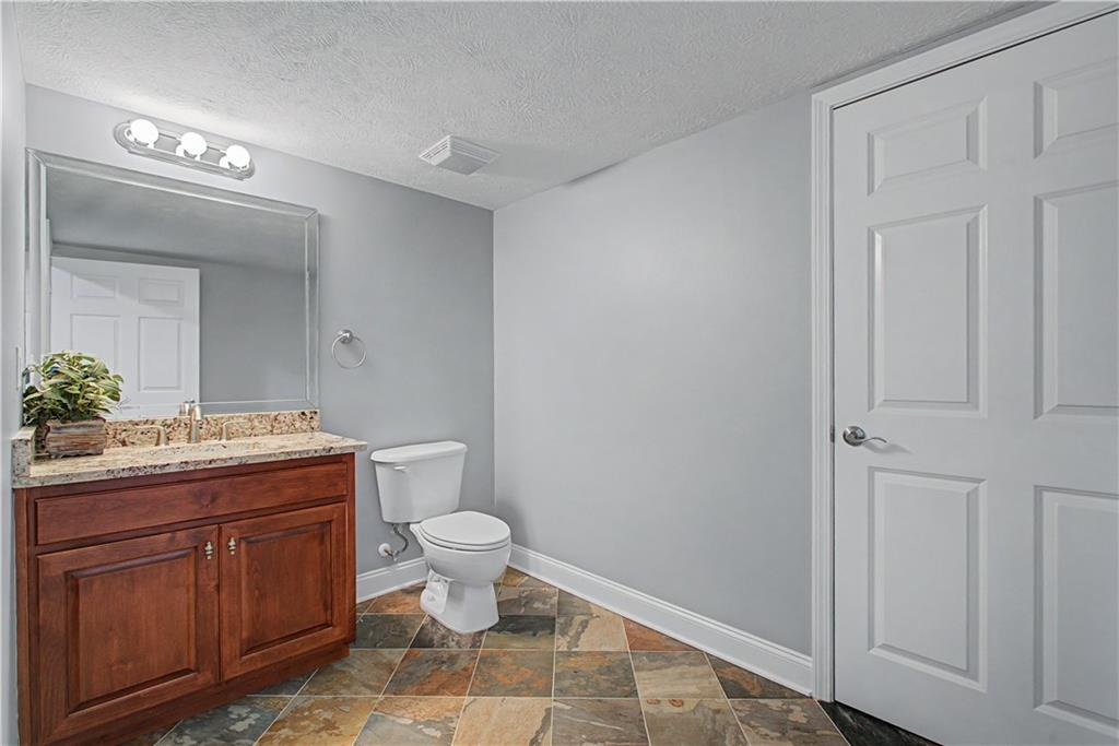 3045 Camp Branch Road Buford, GA 30519 - Photo 56 of 76 a spacious bathroom with a granite countertop toilet a mirror and a sink