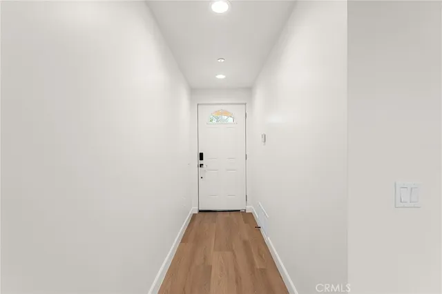 a view of a hallway with wooden floor and a bathroom