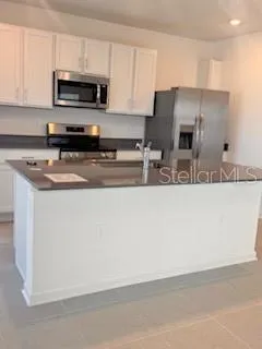 a kitchen with stainless steel appliances granite countertop a sink a stove a microwave and wooden cabinets