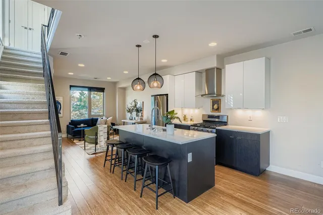 a kitchen with stainless steel appliances granite countertop a stove a sink dishwasher and a dining table with wooden floor