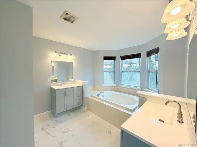 a bathroom with a tub sink and mirror