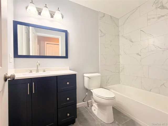 a bathroom with a bathtub shower sink mirror and toilet