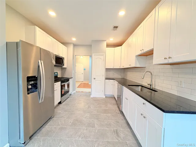 a large kitchen with stainless steel appliances sink a microwave and cabinets