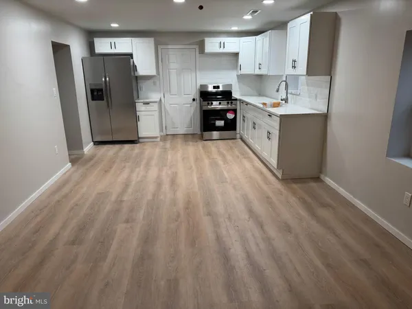 a large kitchen with a lot of white cabinets and stainless steel appliances