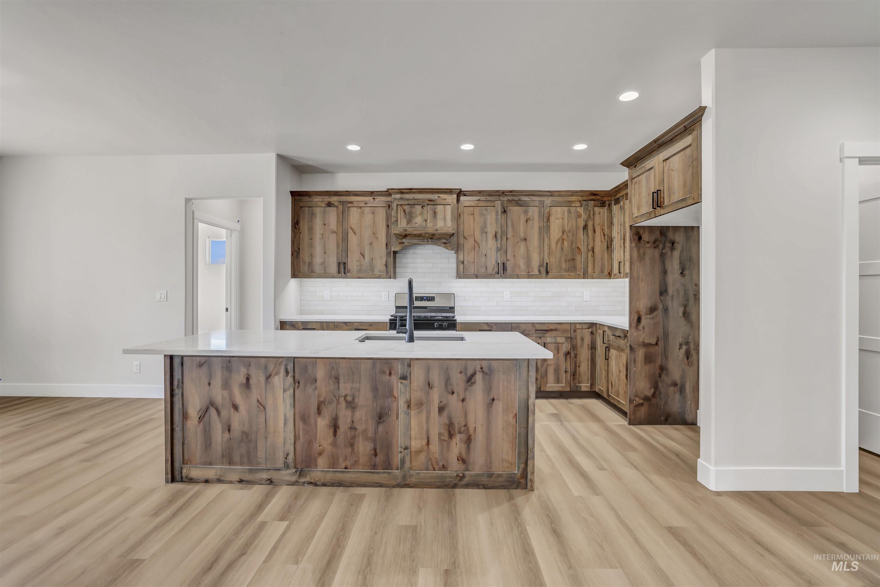 941 Gregory Way Twin Falls, ID 83301 - Photo 11 of 40 Kitchen featuring light wood finished floors, light countertops, tasteful backsplash, a kitchen island with sink, and recessed lighting