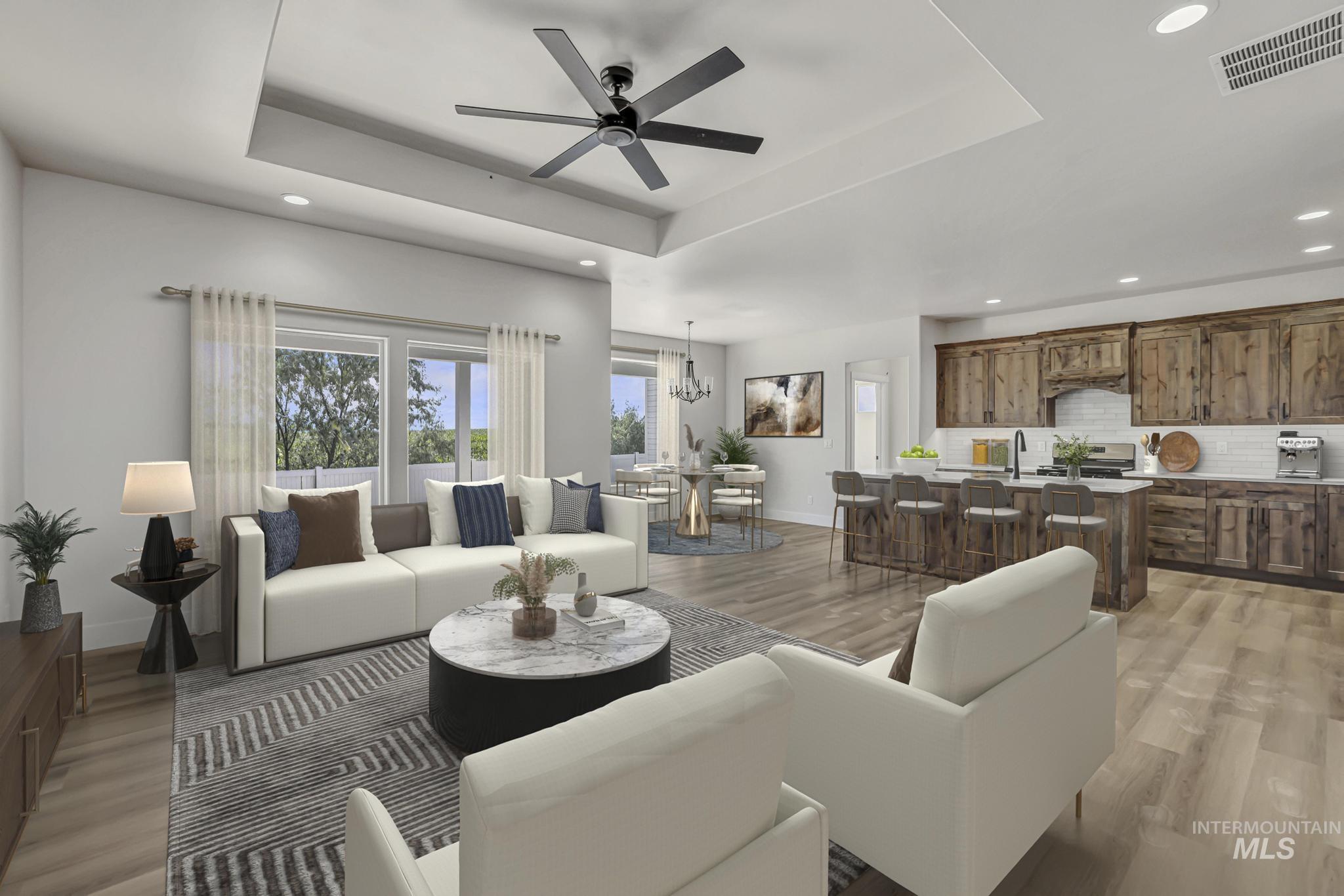 941 Gregory Way Twin Falls, ID 83301 - Photo 2 of 40 Living area with a ceiling fan, a chandelier, light wood-style flooring, healthy amount of natural light, and a tray ceiling