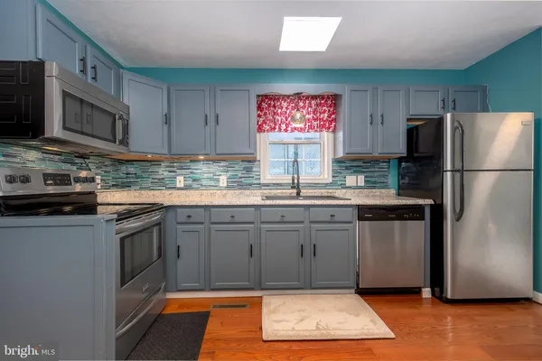a kitchen with stainless steel appliances granite countertop a refrigerator stove top oven and sink
