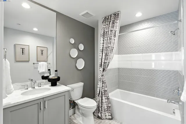 a bathroom with a bathtub shower sink vanity mirror and toilet