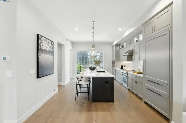 a large kitchen with kitchen island a counter top space a sink stainless steel appliances and cabinets