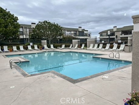210 Lille Lane, Unit 218 Newport Beach, CA 92663 - Photo 44 of 45 a view of a swimming pool with a lawn chairs and potted plants