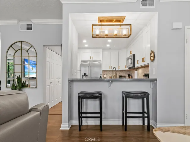 a living room with stainless steel appliances kitchen island a table and chairs in it