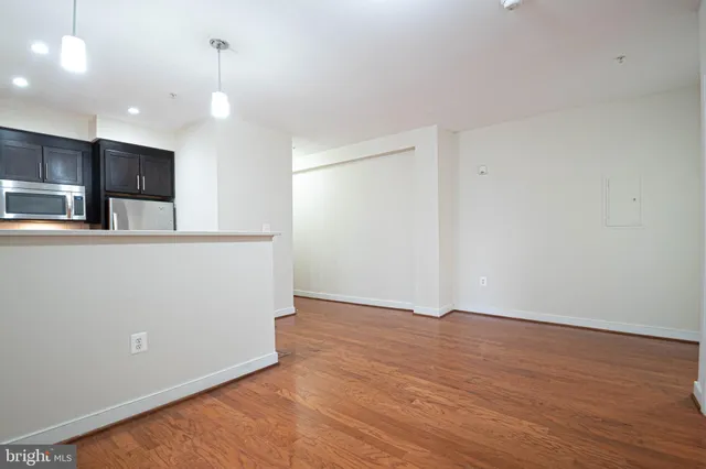 an empty room with wooden floor and stainless steel appliances