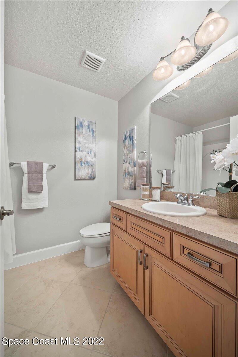 3126 Arden Circle Melbourne, FL 32934 - Photo 26 of 31 a spacious bathroom with a granite countertop sink a toilet and a mirror