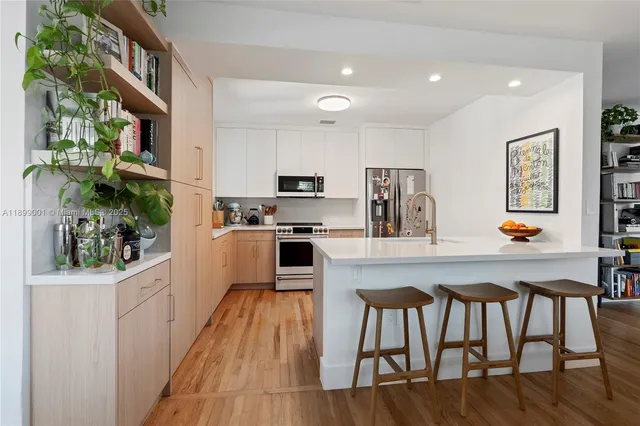 a kitchen with stainless steel appliances granite countertop a table chairs refrigerator and microwave