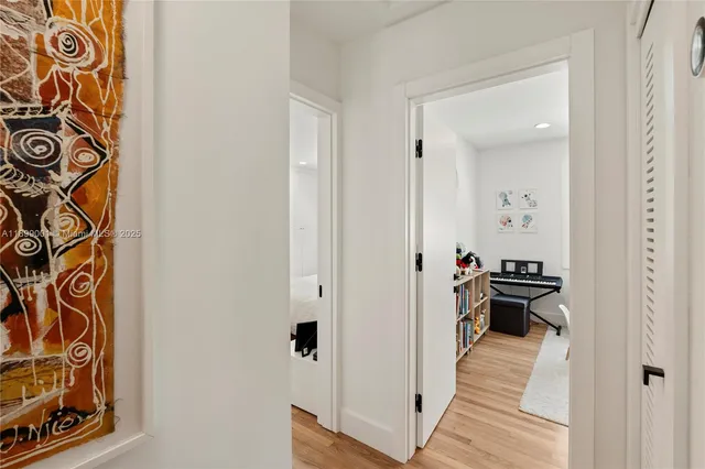 a view of a hallway with wooden floor and a bathroom