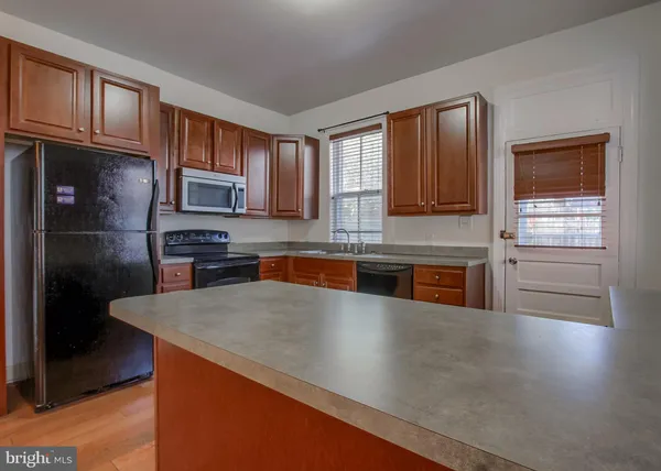 a kitchen with stainless steel appliances granite countertop a refrigerator a stove top oven and a sink with dishwasher