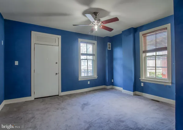 a view of an empty room with chandelier fan and windows