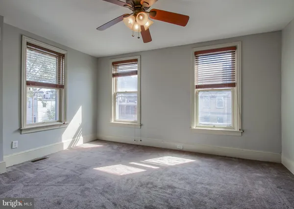 a view of an empty room with chandelier fan and fire place