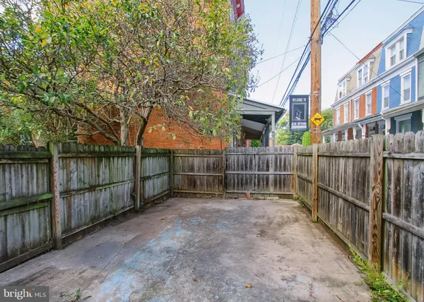 a view of backyard with wooden fence and large trees