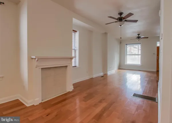 a view of empty room with wooden floor and fan