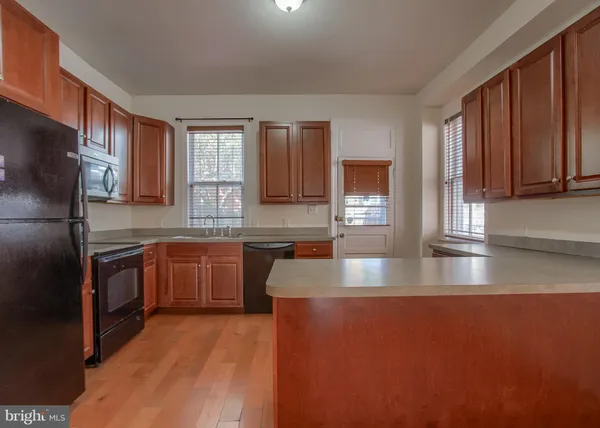 a kitchen with stainless steel appliances granite countertop a refrigerator a sink dishwasher a stove top oven and granite countertops with wooden floor
