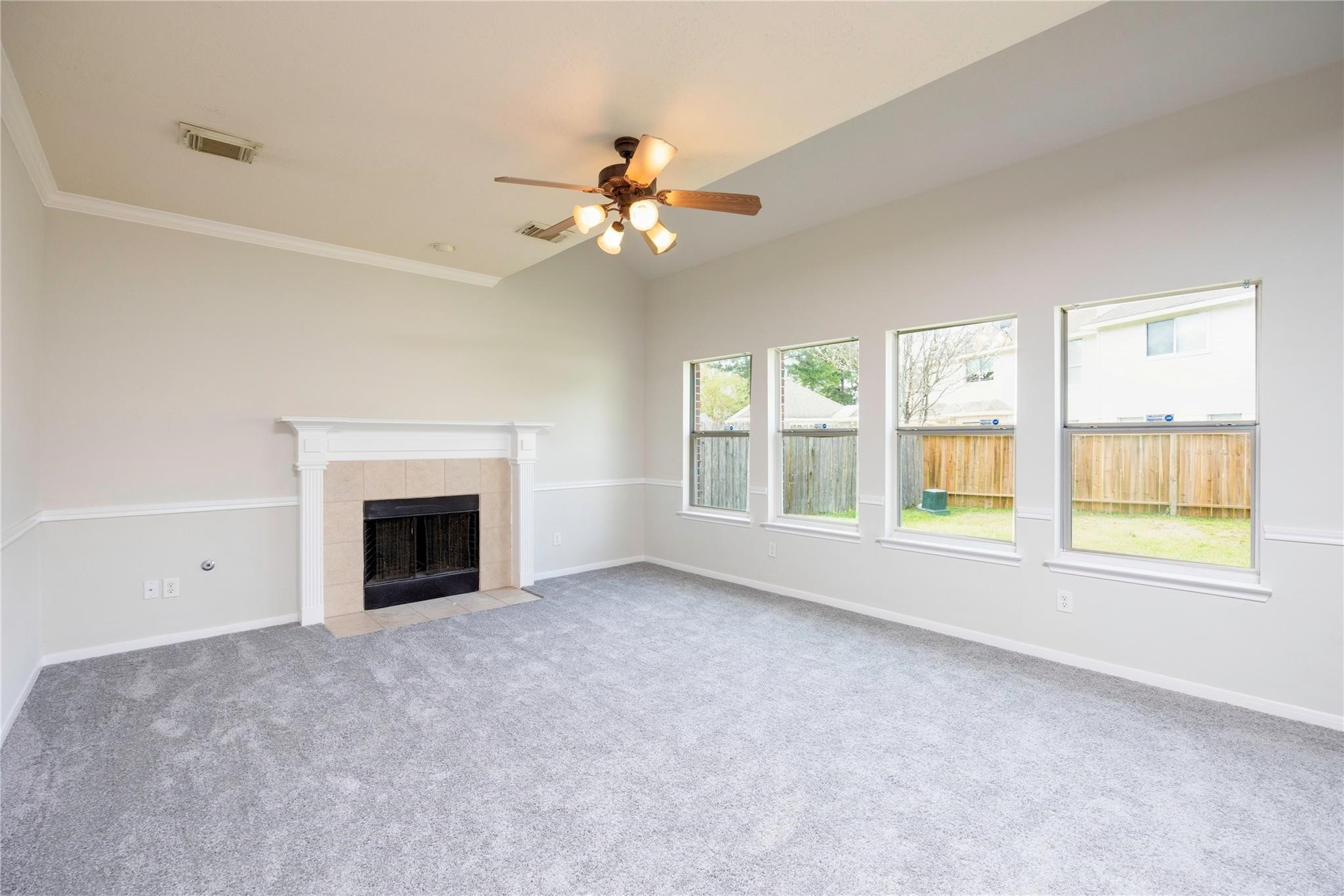 an empty room with windows and fireplace