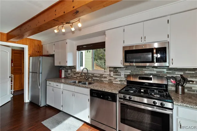 a kitchen with stainless steel appliances a stove a sink and a microwave