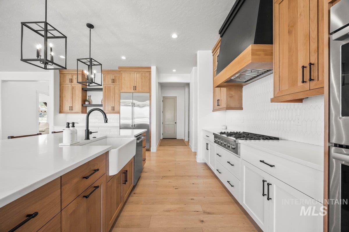 13746 North Ruffed Grouse Way Boise, ID 83714 - Photo 9 of 43 Kitchen with appliances with stainless steel finishes, custom range hood, recessed lighting, tasteful backsplash, and light countertops