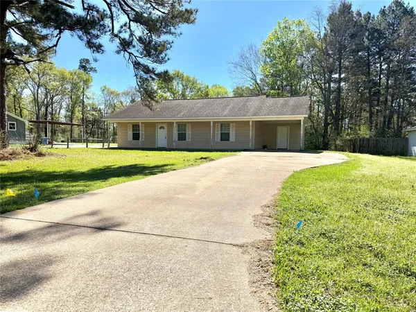 a front view of house with yard and trees in the background